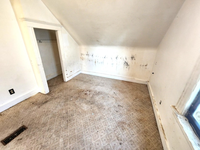 additional living space with visible vents, baseboards, carpet, and vaulted ceiling