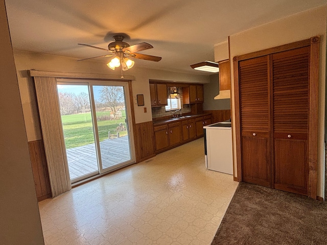 8233 Farrand Rd, Otisville, MI 48463 - kitchen featuring brown cabinets, a wainscoted wall, under cabinet range hood, dark countertops, and a ceiling fan