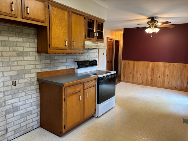 8233 Farrand Rd, Otisville, MI 48463 - kitchen featuring a ceiling fan, electric stove, brown cabinets, a wainscoted wall, and under cabinet range hood