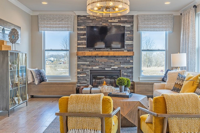 living area featuring an inviting chandelier, a fireplace, crown molding, recessed lighting, and wood finished floors