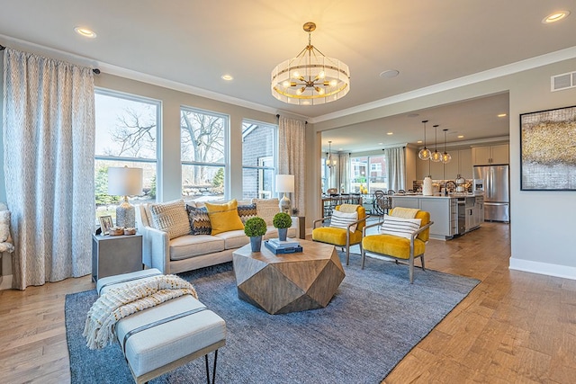 living area with ornamental molding, light wood-type flooring, and a chandelier