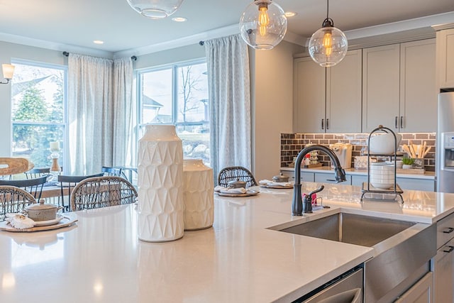kitchen featuring light countertops, decorative light fixtures, a sink, and a wealth of natural light