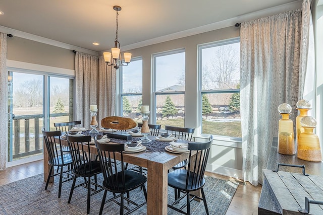 dining area with ornamental molding, a wealth of natural light, a chandelier, and wood finished floors