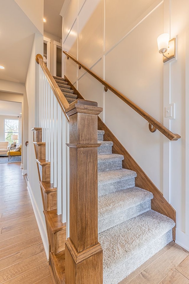stairway with wood finished floors, baseboards, and recessed lighting