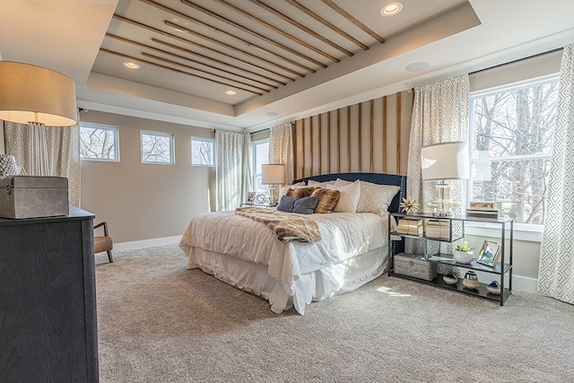carpeted bedroom featuring recessed lighting, a tray ceiling, and baseboards