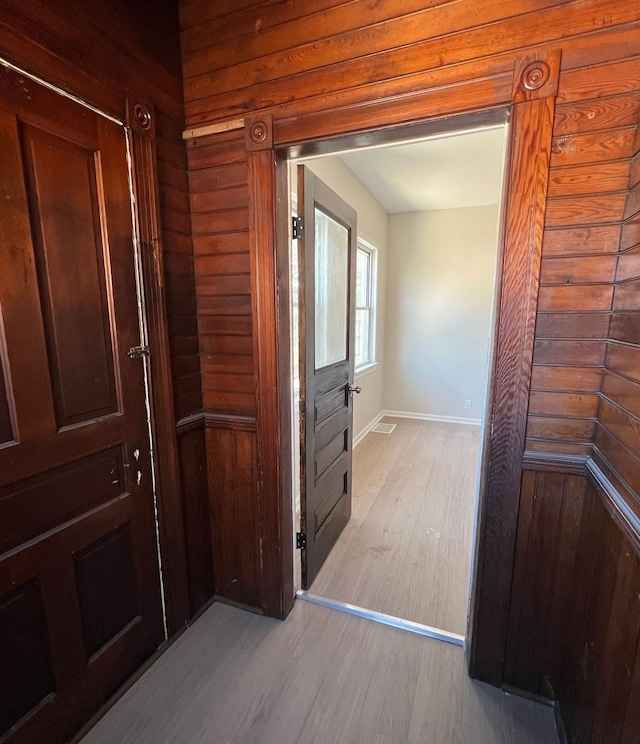 corridor with wooden walls, wood finished floors, and baseboards