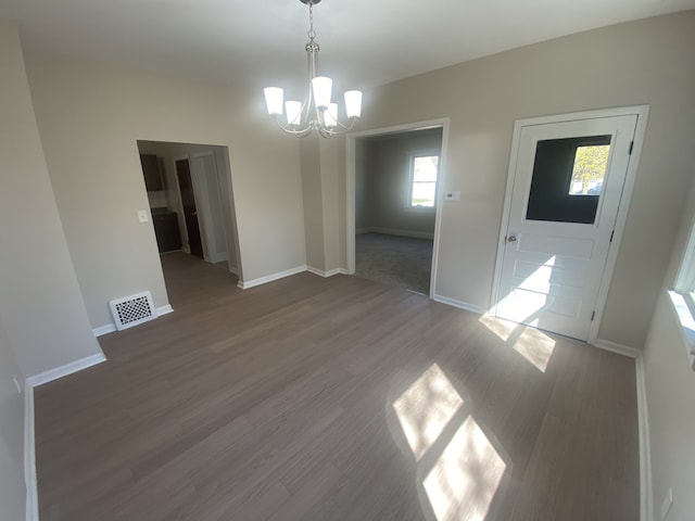 unfurnished dining area featuring a chandelier, wood finished floors, visible vents, and baseboards