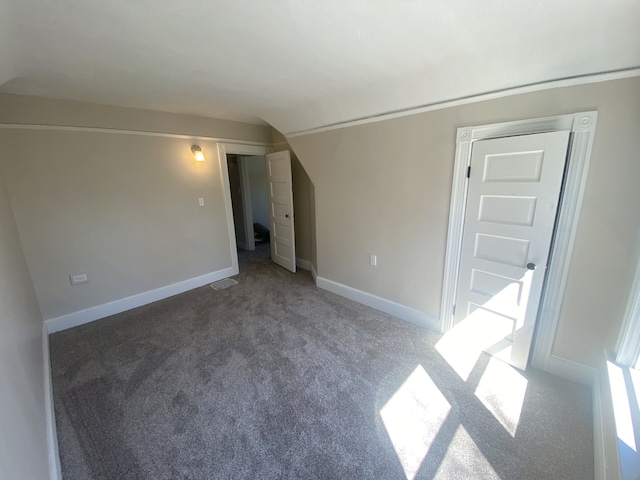 interior space featuring lofted ceiling, baseboards, and carpet floors