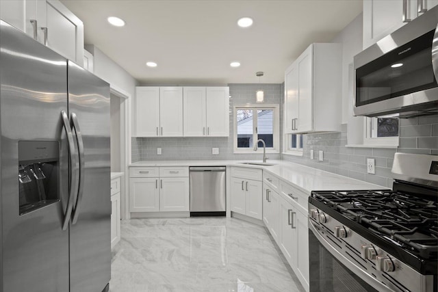 kitchen with tasteful backsplash, light countertops, white cabinetry, appliances with stainless steel finishes, and a sink