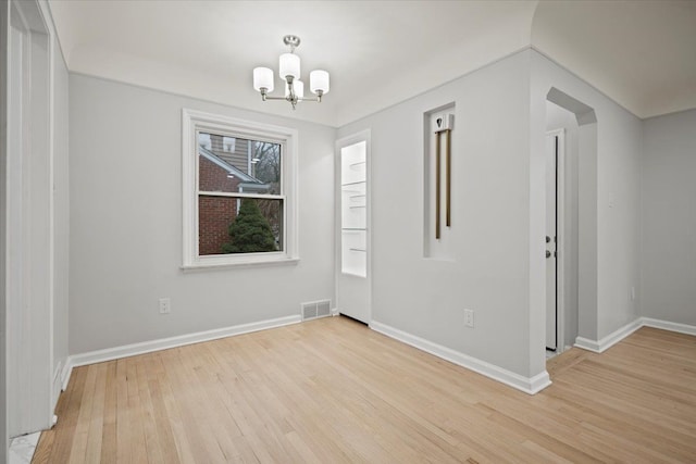 unfurnished room with visible vents, light wood-style flooring, a notable chandelier, and baseboards