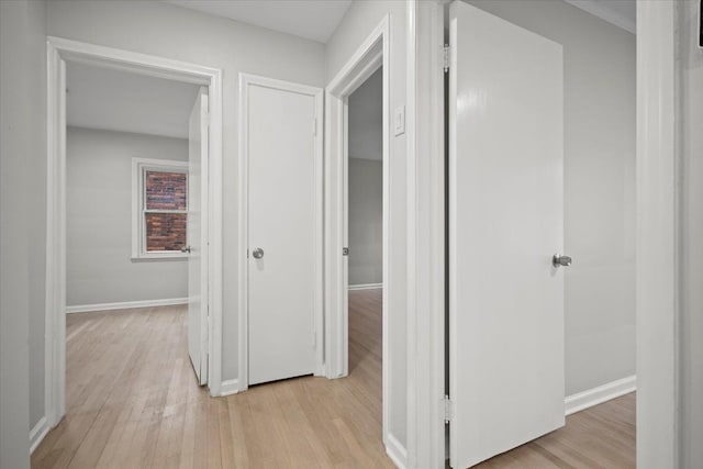 corridor featuring light wood finished floors and baseboards