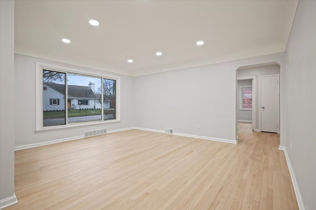 empty room featuring light wood finished floors, baseboards, and visible vents