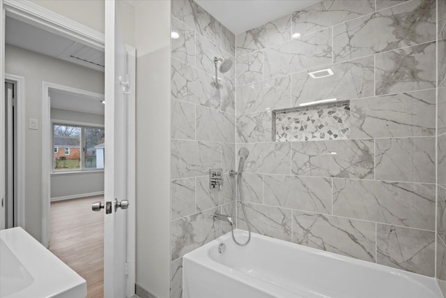 bathroom with bathtub / shower combination, wood finished floors, and baseboards