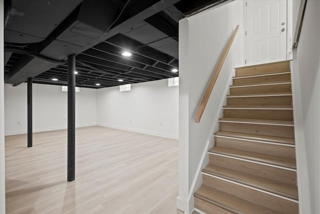 finished basement featuring stairs, baseboards, and wood finished floors