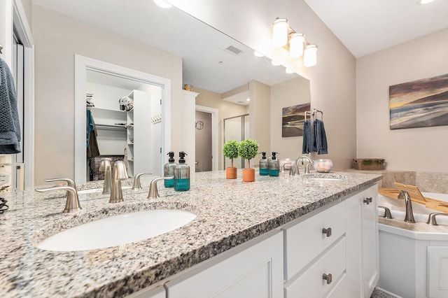 bathroom featuring a bath, double vanity, a sink, and visible vents