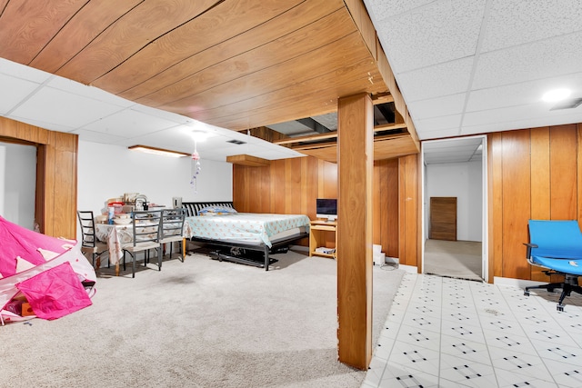 carpeted bedroom featuring a paneled ceiling, wood walls, and visible vents