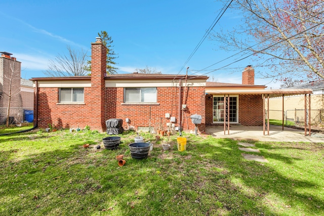 back of house with a yard, brick siding, and a chimney