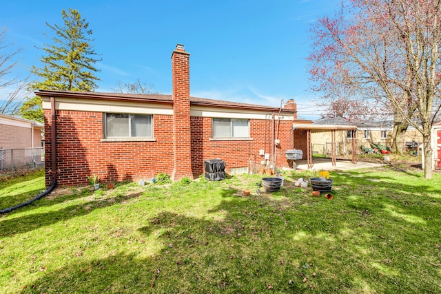 rear view of house with a yard, fence, brick siding, and a patio