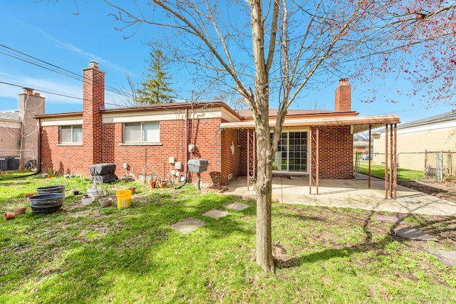 back of property with a yard, a patio, fence, brick siding, and a chimney