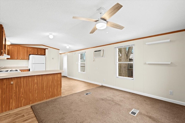 kitchen with visible vents, light countertops, freestanding refrigerator, under cabinet range hood, and vaulted ceiling