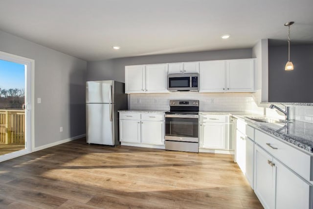 20836 Rolling Hills Ln, Big Rapids, MI 49307 - kitchen featuring appliances with stainless steel finishes, light stone counters, white cabinetry, backsplash, and light wood-style flooring