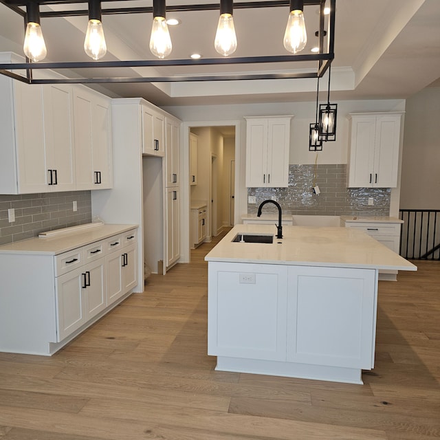 kitchen with a sink, decorative backsplash, and a tray ceiling