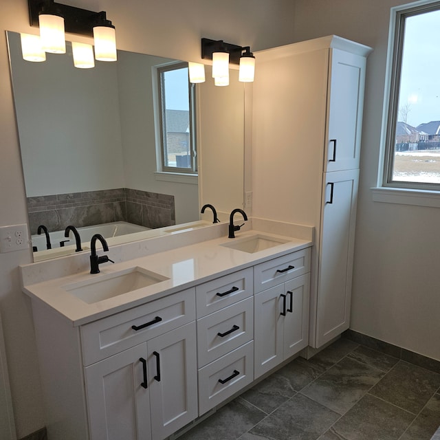 full bathroom featuring double vanity, baseboards, and a sink