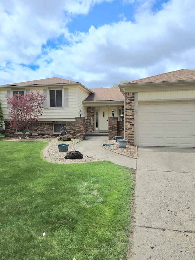 14879 Riverside St, Livonia, MI 48154 - tri-level home with concrete driveway, a front yard, a garage, and brick siding