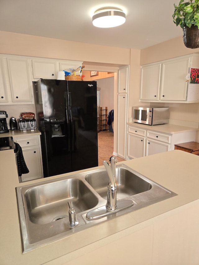 14879 Riverside St, Livonia, MI 48154 - kitchen featuring black fridge, stainless steel microwave, white cabinets, and light countertops
