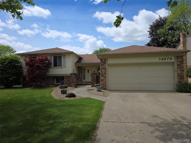 14879 Riverside St, Livonia, MI 48154 - split level home featuring a garage, a front yard, concrete driveway, and brick siding