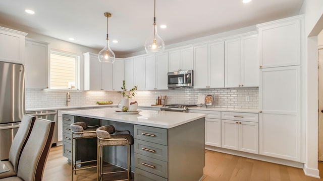 kitchen with light wood-style floors, white cabinets, a center island, appliances with stainless steel finishes, and light countertops