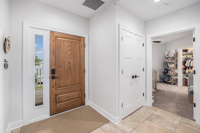 foyer featuring light carpet, light tile patterned floors, visible vents, and baseboards