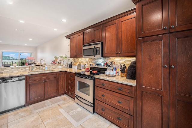 kitchen featuring tasteful backsplash, recessed lighting, light stone countertops, appliances with stainless steel finishes, and a sink