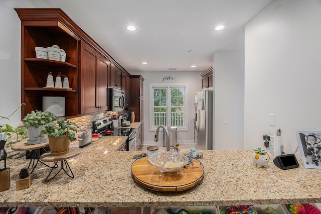 kitchen featuring tasteful backsplash, light stone counters, recessed lighting, a peninsula, and appliances with stainless steel finishes