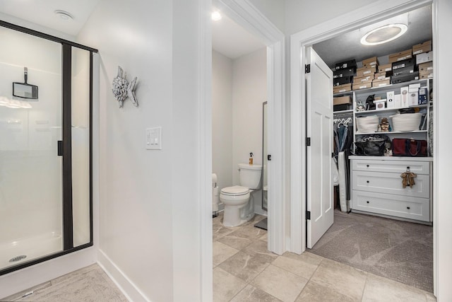 full bathroom featuring a walk in closet, toilet, a shower stall, and baseboards