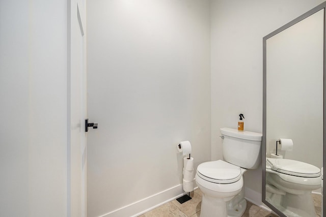 half bathroom with toilet, tile patterned floors, and baseboards