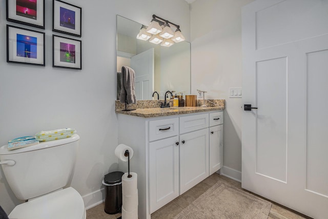 bathroom featuring toilet, baseboards, and vanity