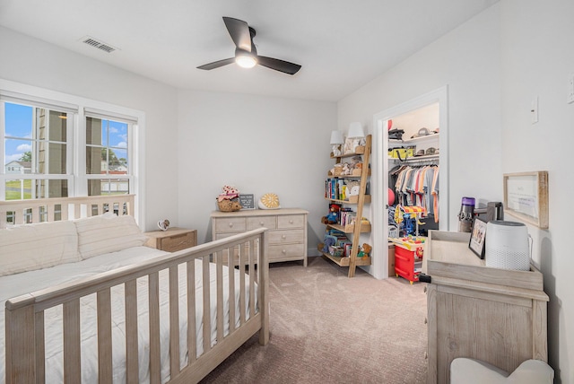bedroom featuring visible vents, a closet, a ceiling fan, a walk in closet, and light colored carpet