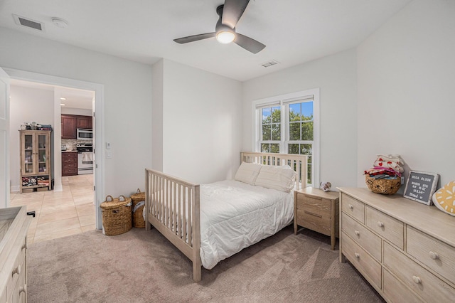 bedroom featuring light carpet, light tile patterned floors, visible vents, and ceiling fan