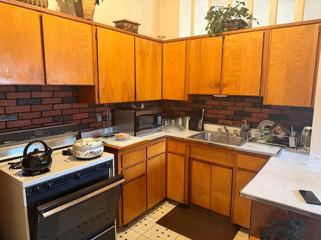 kitchen featuring stainless steel microwave, light countertops, a sink, and gas range gas stove