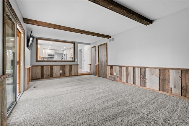 3715 W Hiawatha Dr, Okemos, MI 48864 - carpeted empty room with beam ceiling, a wainscoted wall, visible vents, and wood walls
