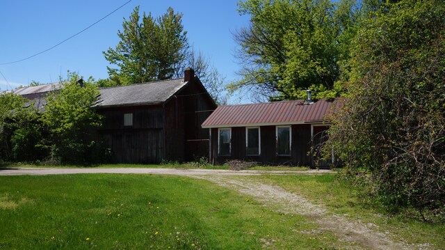 11340 Mccrone Rd, Milan, MI 48160 - view of front facade featuring a front yard, metal roof, and a chimney