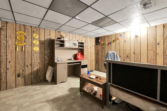 basement featuring wooden walls, tile patterned floors, and a paneled ceiling