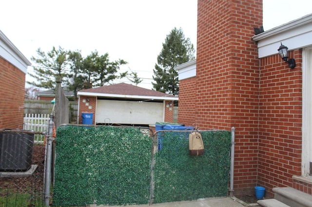 view of property exterior with brick siding, central AC, an outdoor structure, fence, and a garage