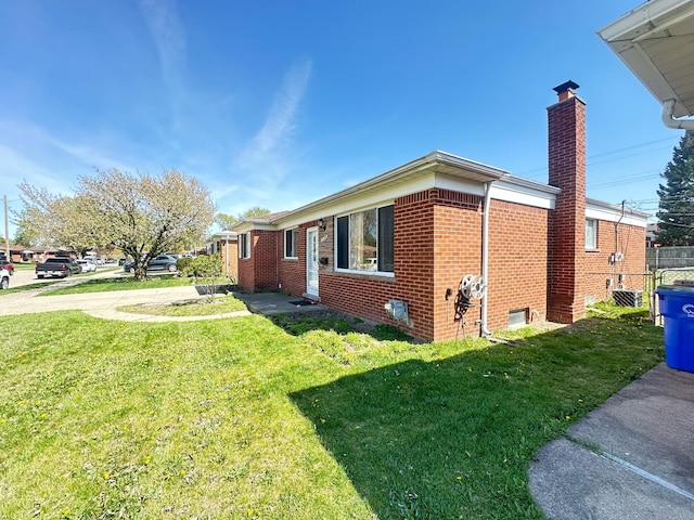 view of side of property featuring brick siding, a chimney, and a lawn