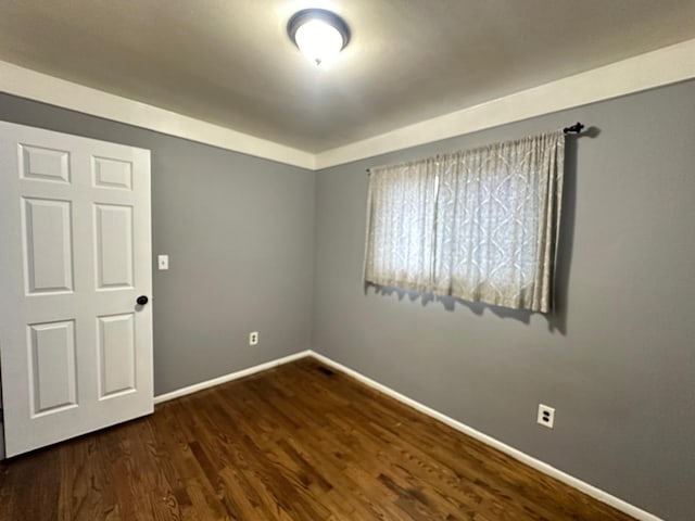 spare room featuring dark wood finished floors and baseboards