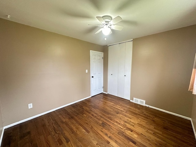 unfurnished bedroom featuring baseboards, dark wood-style flooring, a closet, and a ceiling fan