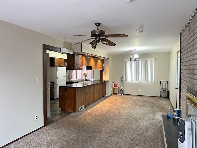 kitchen featuring freestanding refrigerator, a peninsula, ceiling fan, carpet flooring, and dark countertops