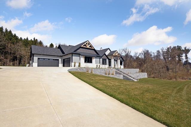 view of front of house with a garage, a front lawn, driveway, and stone siding