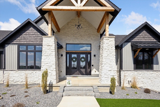 view of exterior entry featuring board and batten siding, french doors, and stone siding